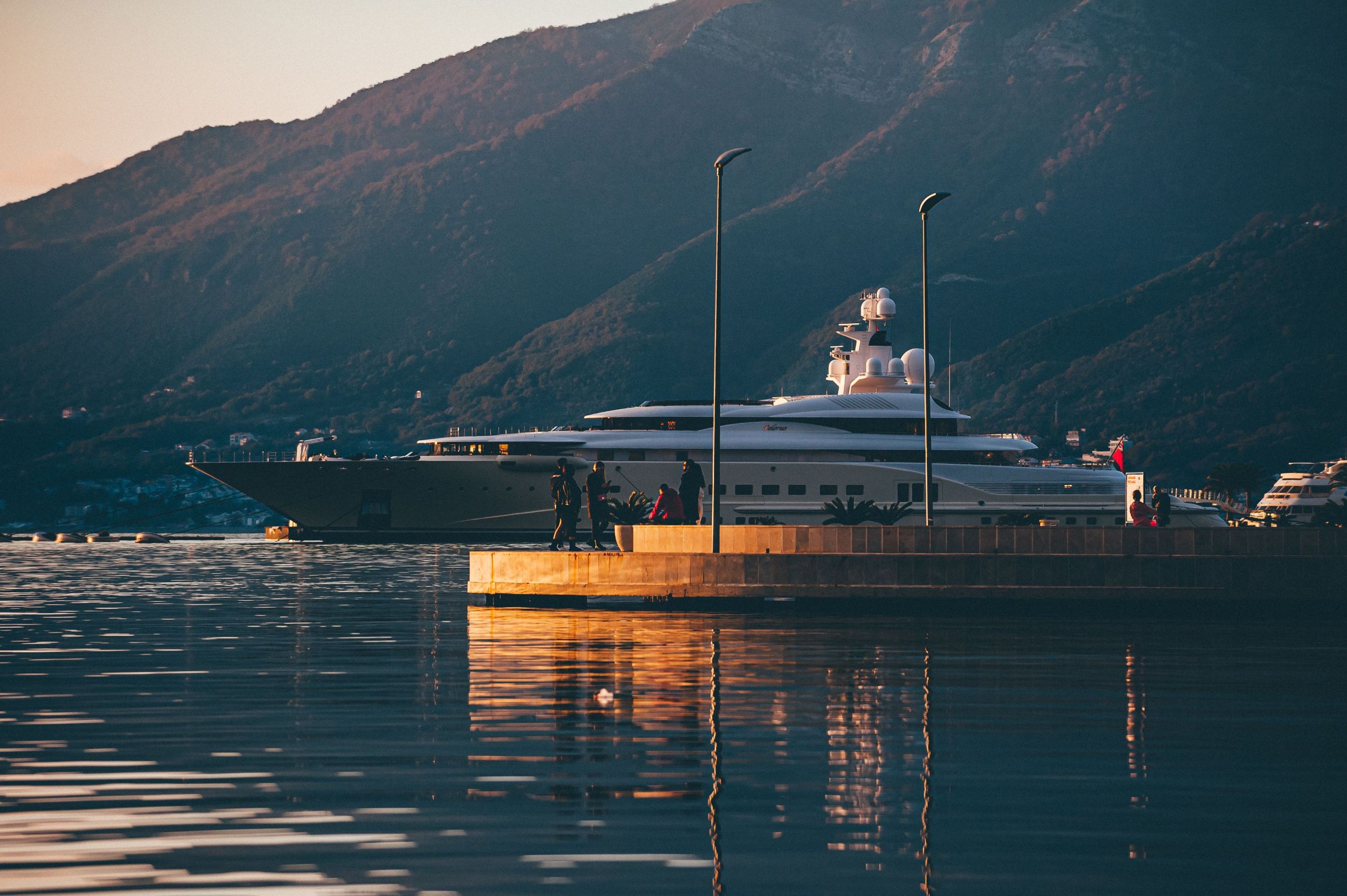 Yacht moored at Porto Montenegro with mountains and calm water in the background.